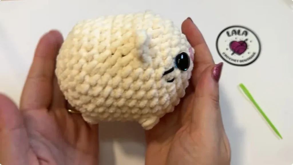 Partially completed crochet cat body with a safety eye