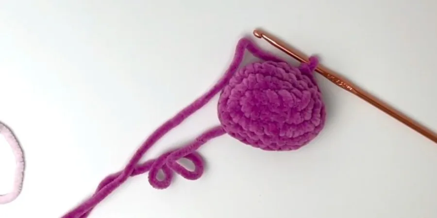 Crocheting the purple snout for a strawberry cow amigurumi using plush yarn and a crochet hook