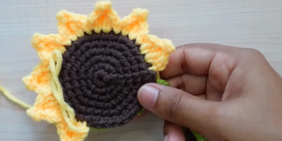 Crochet sunflower with textured yellow petals worked around a dark brown center