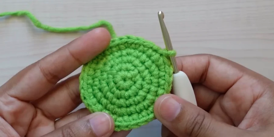 Green crochet sunflower center after round 5 with a wider circular shape