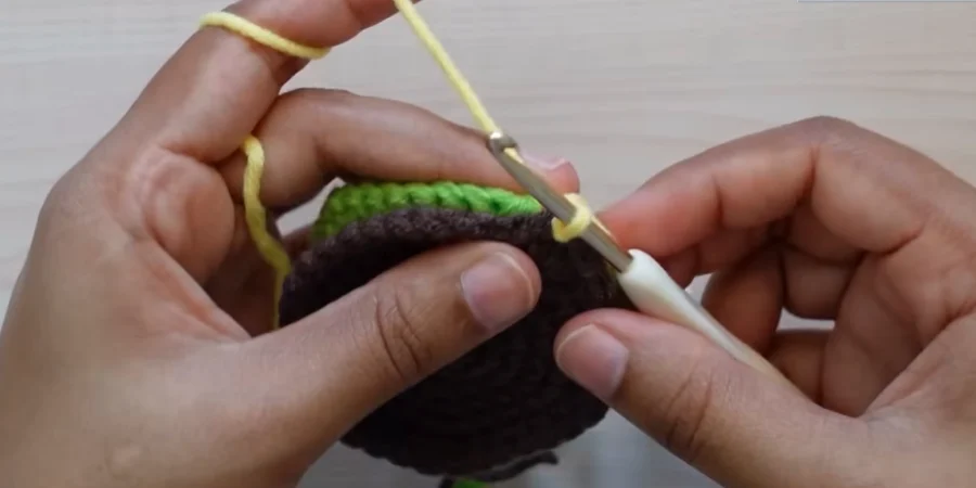 Yellow yarn being joined to two crochet sunflower center pieces for the petal round