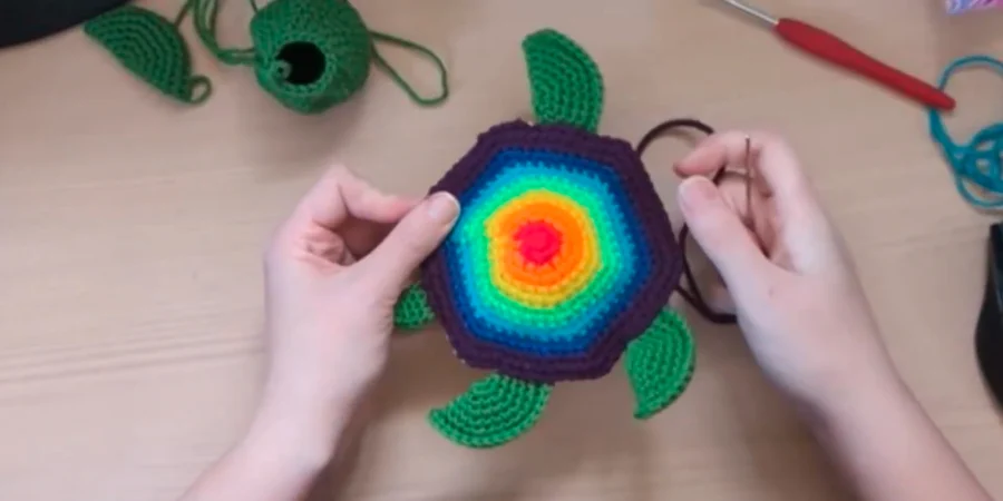 Crocheted turtle shell with rainbow-colored rounds being prepared for assembly.