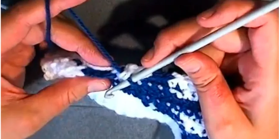 Close-up of Row 12 colorwork on a Crochet Star of David Granny Square with blue and white stitches