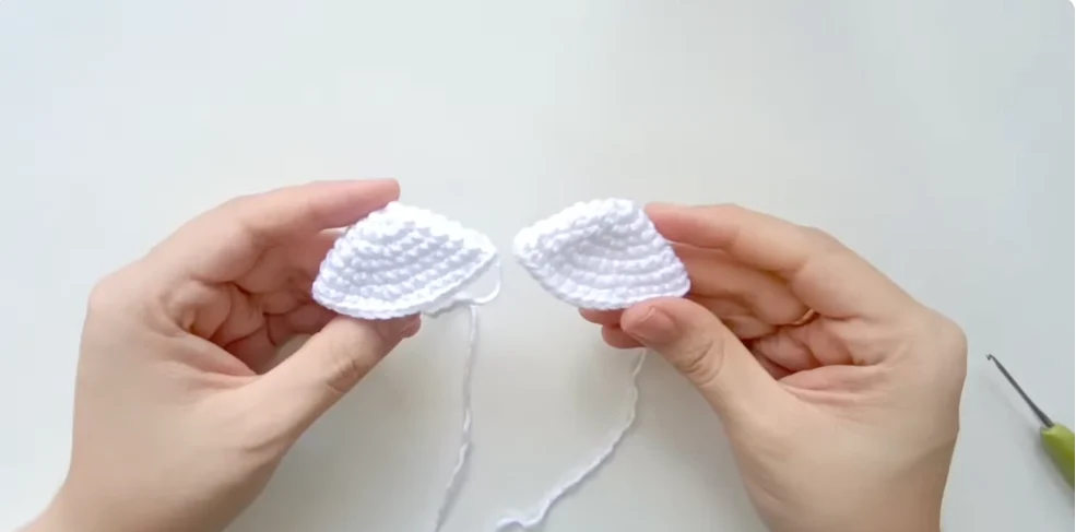 Two crocheted white Hello Kitty ears prepared for attaching to the amigurumi head