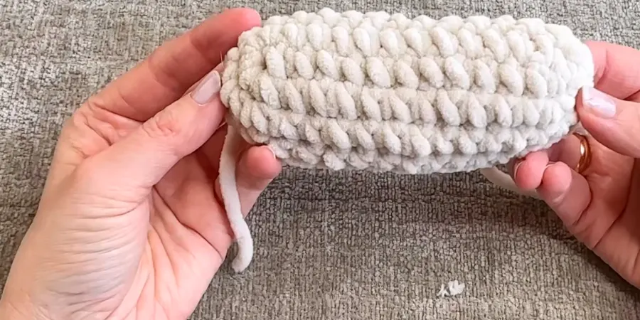 White crocheted muzzle piece displayed in progress, showing its oval shape and textured stitches.