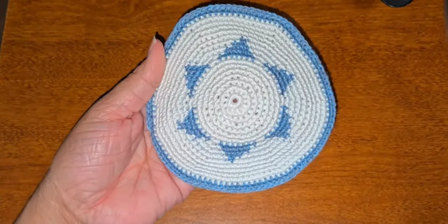 Completed white crocheted kippah featuring a blue Star of David motif and matching blue border.
