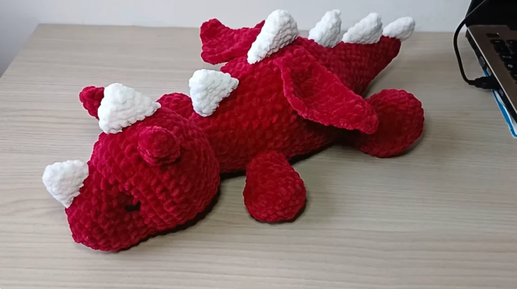 Red and white crochet dragon amigurumi with horns, wings, spikes, and four legs