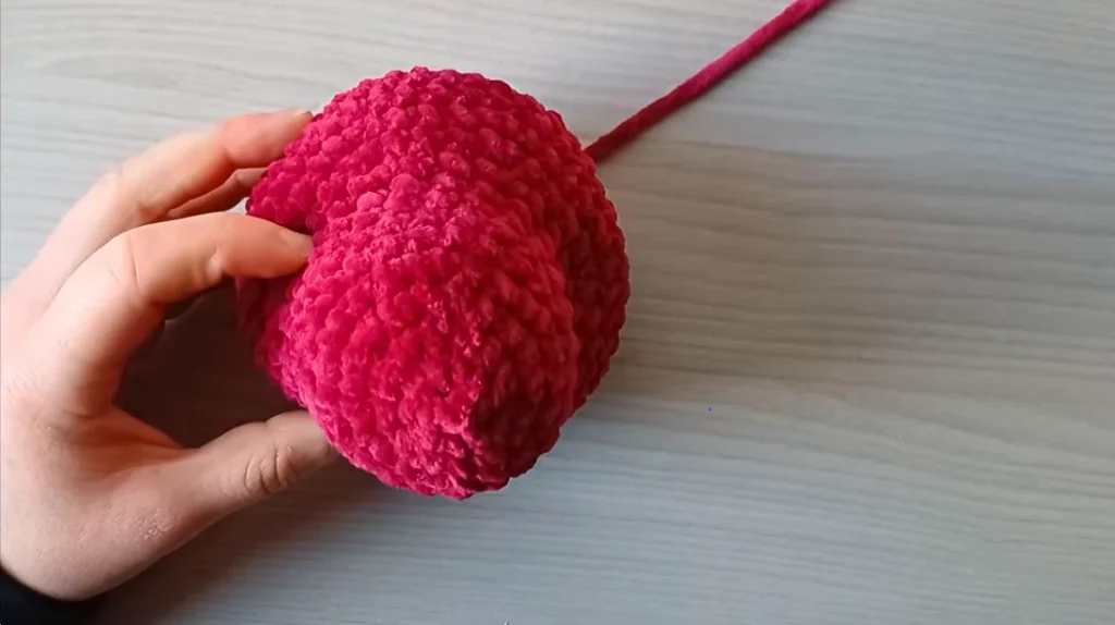 Close-up of a red crocheted dragon head showing the rounded shape and textured stitches