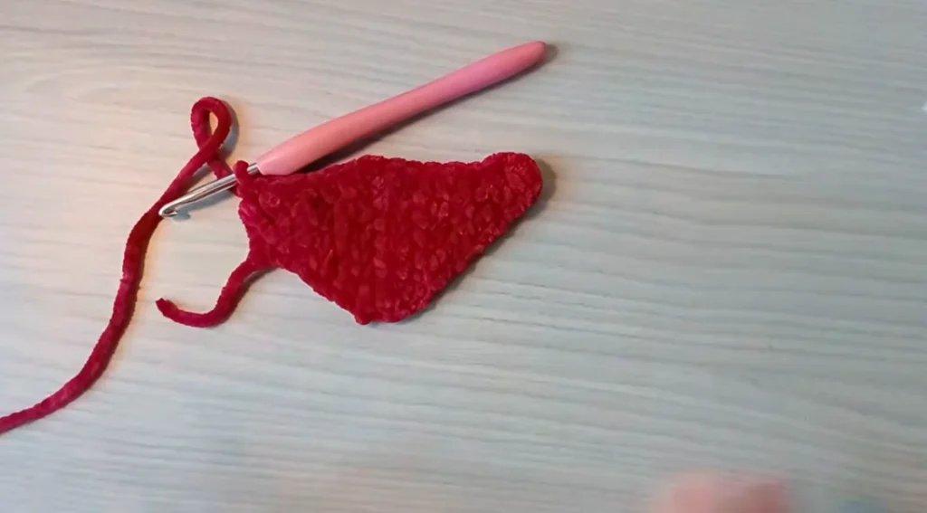 Red crocheted dragon wing piece shaped with pointed edges and a curved design