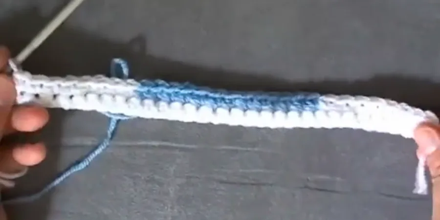 Close-up of a blue and white crochet foundation row being worked with a crochet hook