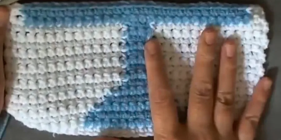Blue and white crochet piece showing the Menorah body and central stem as the pattern takes shape.