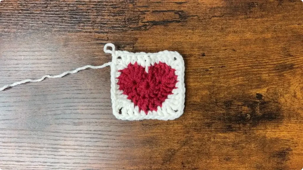 Round 3 showing a red crochet heart being transformed into a square with a white border and defined corners
