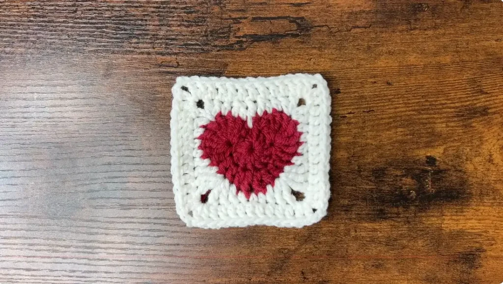 Completed fourth round of a heart granny square with a red heart center and white double crochet border