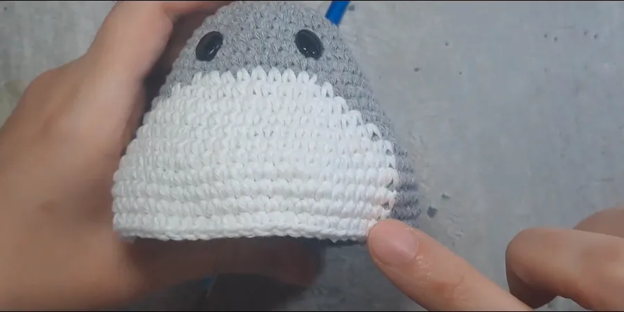 Front view of a crocheted Totoro showing the completed white belly and grey body.