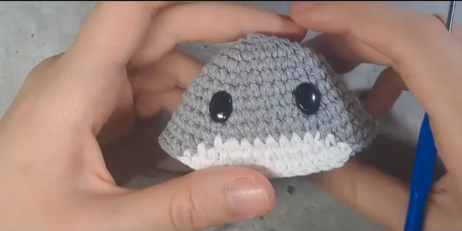 Close-up of a crocheted Totoro body showing the grey and white belly colorwork and black safety eyes.