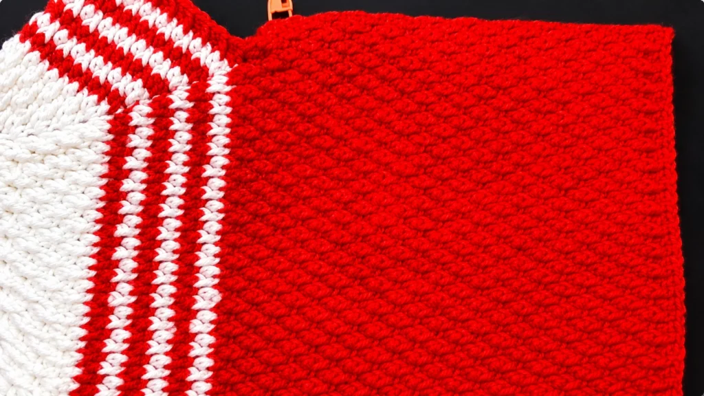 Red crochet panel with a white section and alternating red and white stripes, showing the textured stitches and colorwork detail.