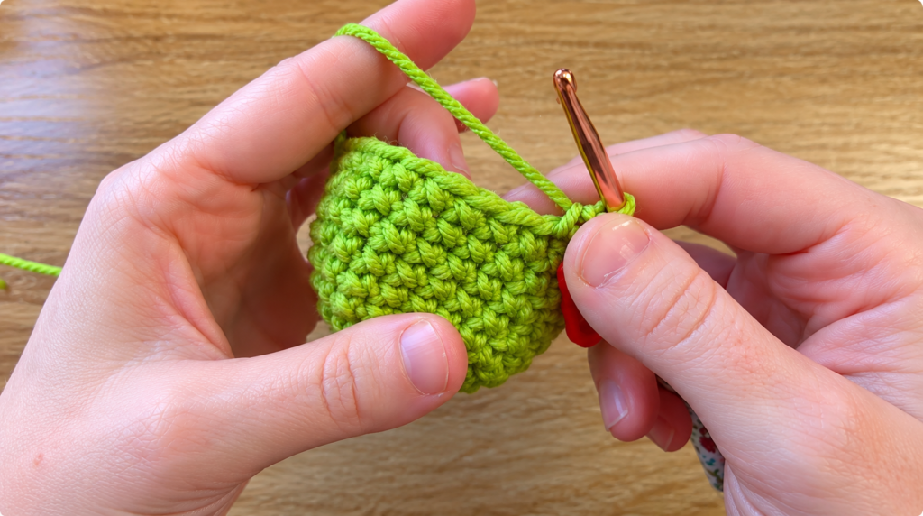Crocheting a lime green amigurumi — Hands using a crochet hook to work lime green stitches on an amigurumi piece.